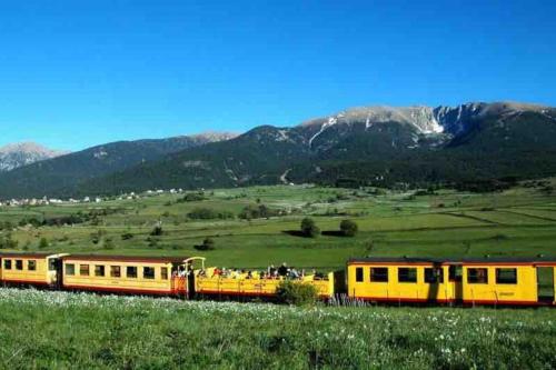 a yellow and red train traveling through a green field at studio cabine Font Romeu in Font Romeu Odeillo Via