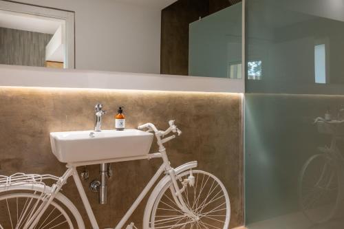 a white bike parked in a bathroom with a sink at Reflexos D'Alma Turismo Rural in Estremoz