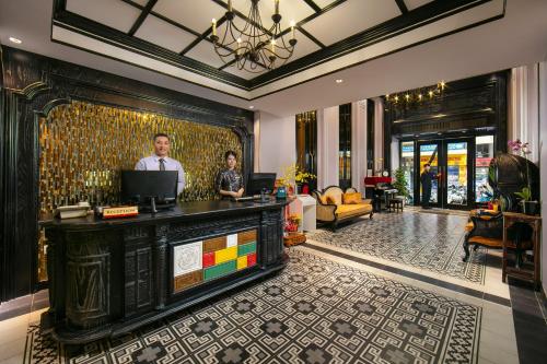 two people standing at a counter in a hotel lobby at Lavender Central Hotel & Spa Hanoi in Hanoi