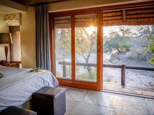a bedroom with a bed and a window with a view at Shimungwe Lodge in Hoedspruit