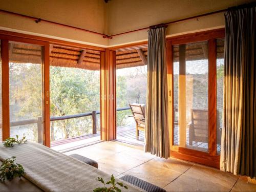 Camera con porte scorrevoli in vetro e balcone. di Shimungwe Lodge, Thornybush Game Reserve a Hoedspruit
