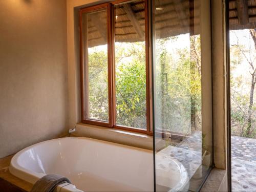 a bath tub in a bathroom with a window at Shimungwe Lodge in Hoedspruit