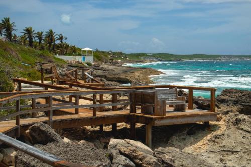 a group of wooden benches on a beach near the ocean at Stella Maris Resort Club in Stella Maris
