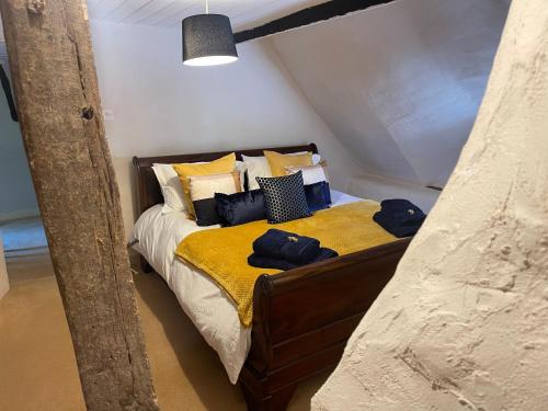 Schlafzimmer mit einem Bett mit gelber Bettwäsche und Kissen in der Unterkunft Beautiful Character Thatched Pet Friendly House in Enford