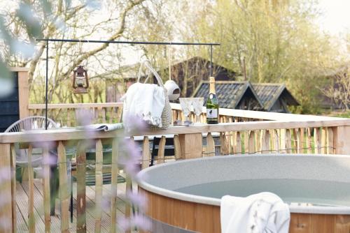 a hot tub on a wooden deck with a table at Smuk Huske in Echtenerbrug