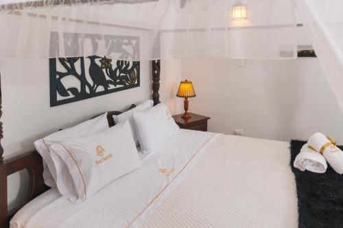 ein Schlafzimmer mit einem weißen Bett mit weißer Bettwäsche und Kissen in der Unterkunft Hotel Cemandy by MA in Villa de Leyva