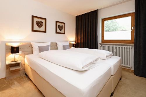 ein großes weißes Bett in einem Zimmer mit Fenster in der Unterkunft Ferienwohnung Karin in Bolsterlang