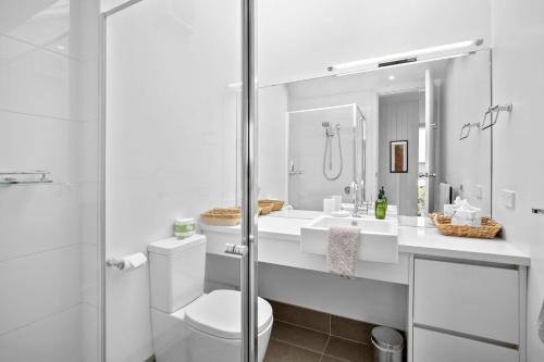 a white bathroom with a toilet and a shower at One At Eight in Lorne