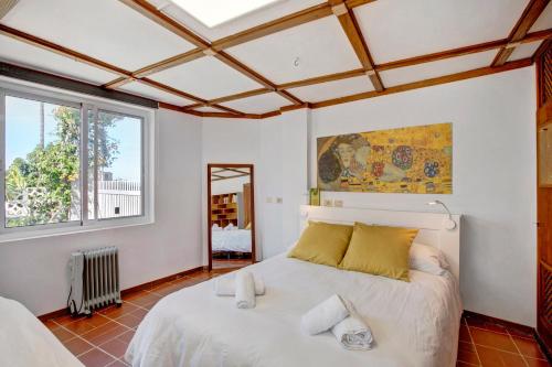 1 dormitorio con 1 cama blanca grande con almohadas amarillas en Casa Los Cipreses, en Puerto de la Cruz