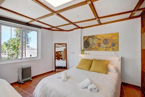 una camera da letto con un grande letto bianco con cuscini gialli di Casa Los Cipreses a Puerto de la Cruz