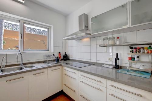 cocina con armarios blancos, fregadero y ventana en Casa Los Cipreses, en Puerto de la Cruz
