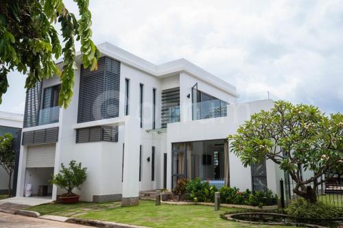 uma casa branca com persianas pretas em Cozrum Luxury - Aria Resort Vũng Tàu em Xã Thắng Nhứt