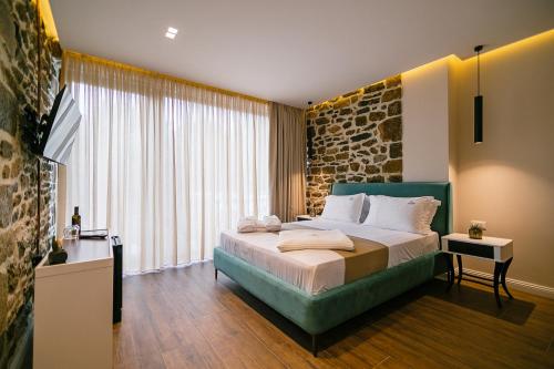 una camera con un grande letto e un muro di pietra di Vecchia Boutique Hotel a Korçë