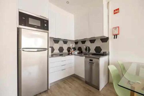 a kitchen with white cabinets and a stainless steel refrigerator at Timeless Beach III Apartment in Armação de Pêra