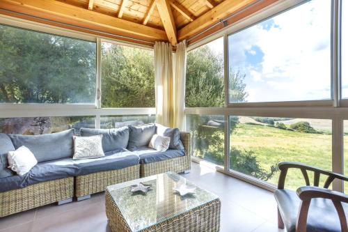 - un salon avec un canapé et de grandes fenêtres dans l'établissement Villa A LICCIA, à Figari