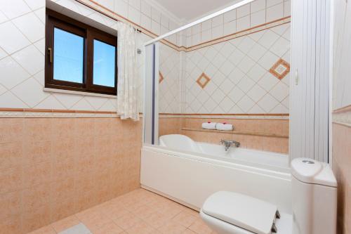 a bathroom with a tub and a toilet and a sink at Zante View villa Odysseus in Planos