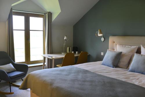 a bedroom with a bed and a desk and a window at B&B Entre Champs in Ohain