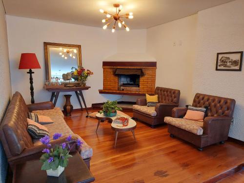 a living room with leather furniture and a fireplace at Hotel Mount Everest in Nova Friburgo