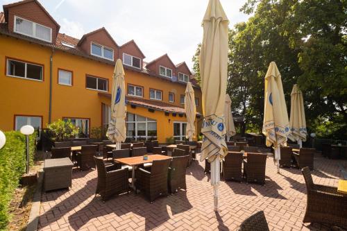 a patio with tables and umbrellas in front of a building at Hotel-Restaurant Weinberg in Artern