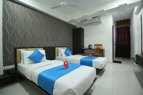 two beds in a hotel room with two red candles on them at The Pacific Hotel in Vadodara