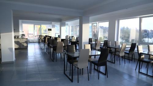 a dining room with tables and chairs and windows at Aventus Hotel in Akhaltsikhe