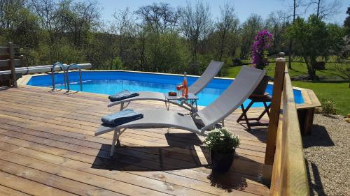 a deck with a table and chairs next to a pool at Gites de Verger, stylish self catering cottages in Sos in Sos