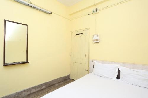 a bedroom with a white bed and a mirror at Hotel O Surya in Rourkela