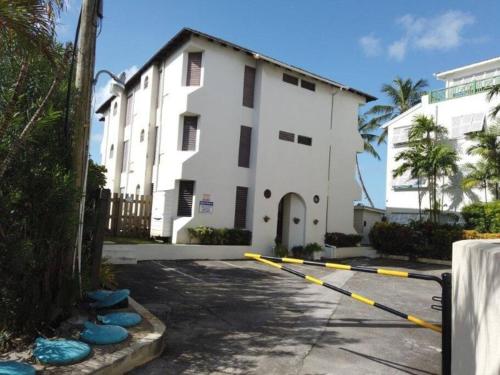 a white building with yellow poles in front of it at 6 Sandy Surf, Worthing Christ Church in Christ Church