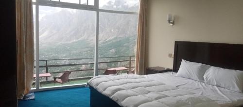 a bedroom with a bed and a large window at Venus Mountain Resort, Hunza in Hunza Valley