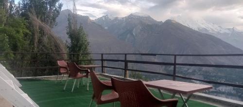 a balcony with tables and chairs and a view of mountains at Venus Mountain Resort, Hunza in Hunza