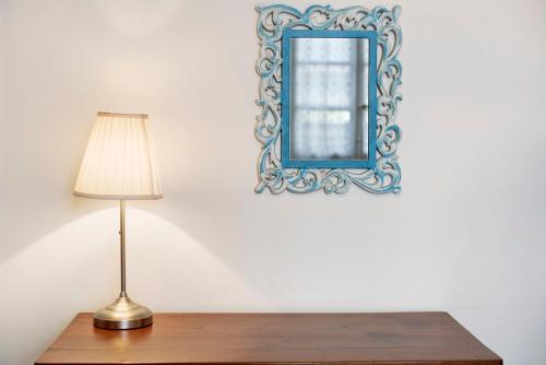 a table with a lamp and a mirror on a wall at A due passi dal mare in Chiavari