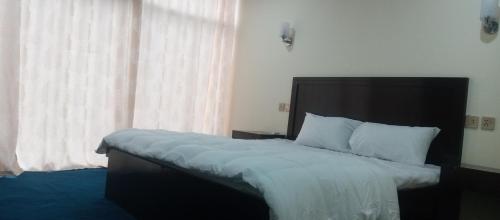a bedroom with a bed with a black headboard and a window at Venus Mountain Resort, Hunza in Hunza