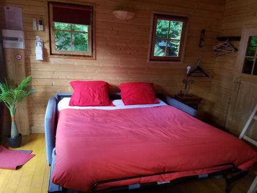 ein Schlafzimmer mit einem großen roten Bett mit zwei roten Kissen in der Unterkunft Normandy cottage in Gagny