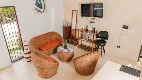 a living room with wicker chairs and a television at Hotel Nojoch che in Cobá