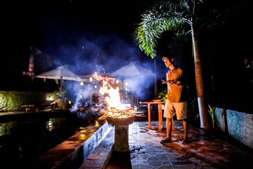 a man standing in front of a fire at night at The Granyam Garden Cottage in Nusa Penida