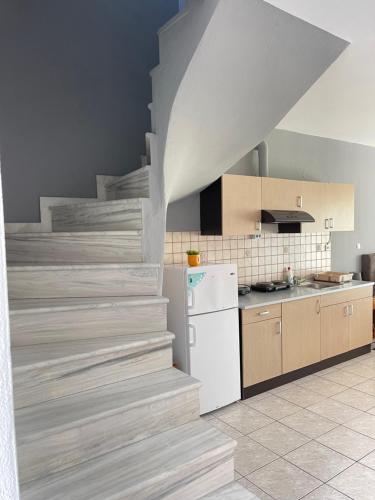 a kitchen with a staircase with a white refrigerator and a counter at Artemis Hotel Apartments in Keramotí