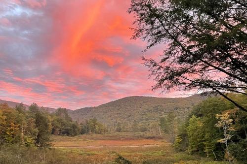 a rainbow in the sky over a field with trees at The Pond House in Plymouth