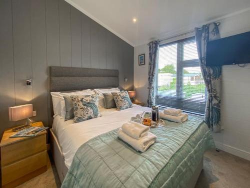 um quarto com uma cama com duas toalhas em Alde Lodge - 5 mins from beach with EV Point em Aldeburgh