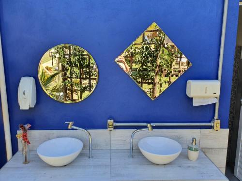 a bathroom with two sinks and two mirrors on the wall at João de Barro camping e suítes in Alto Paraíso de Goiás