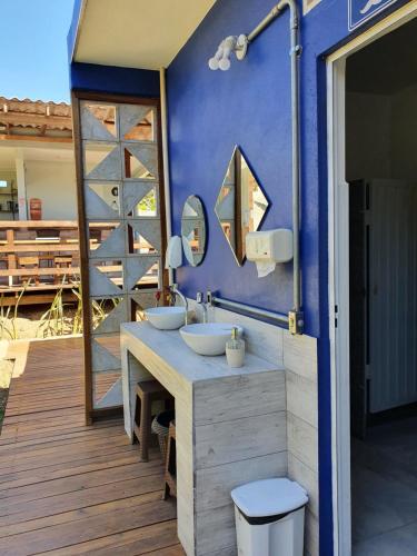 uma casa de banho com 2 lavatórios e uma parede azul em João de Barro camping e suítes em Alto Paraíso de Goiás