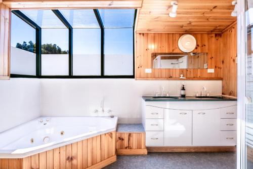 a bathroom with a tub and a large window at The Boathouse - Freycinet Holiday Houses in Coles Bay