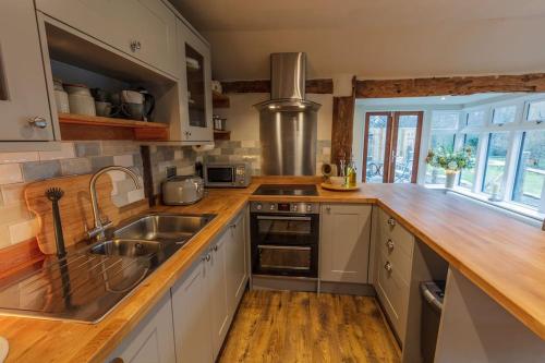 a kitchen with white cabinets and a wooden counter top at Halfmoon Lodge @ Knights Hole wheelchair access in Cranbrook