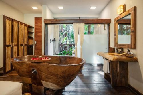La salle de bains est pourvue d'une baignoire en bois et d'un lavabo. dans l'établissement Kanan Tulum Treehouse, Rooftop, Beach Club & Spa - Adults Only, à Tulum
