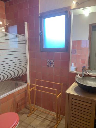 La salle de bains est pourvue d'un lavabo, d'une baignoire et d'une fenêtre. dans l'établissement Gîte à Poggiale de Figari, à Figari