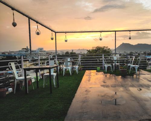 a group of tables and chairs on a roof with the sunset at Hotel Lake Bridge in Udaipur