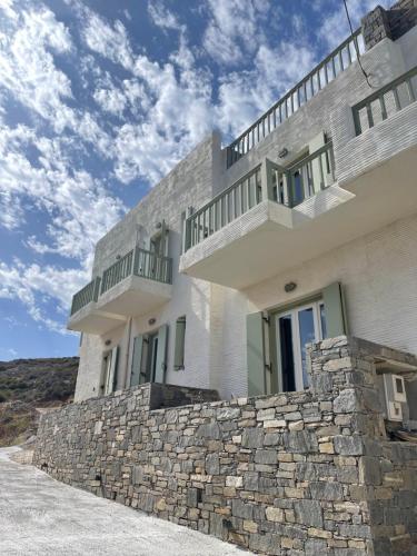 a white building with a stone retaining wall at Kalderimi Big Blue Cyclades Syros in Vári