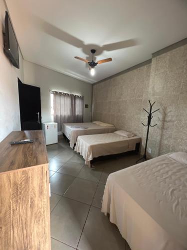 a hotel room with two beds and a ceiling fan at Hotel Ibirapuera in Barretos