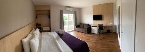 um quarto de hotel com uma cama e uma sala de estar em Legacy Hotel Guaratinguetá - Ao lado de Aparecida -SP em Guaratinguetá