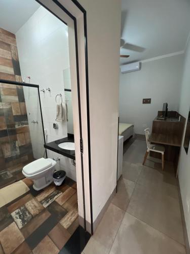 a bathroom with a toilet and a sink at Hotel Ibirapuera in Barretos