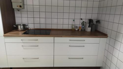 a kitchen with white cabinets and a wooden counter top at Zimmer in Ramstein in Ramstein-Miesenbach